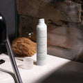 Skincare bottle on a bathroom counter with a stone wall background