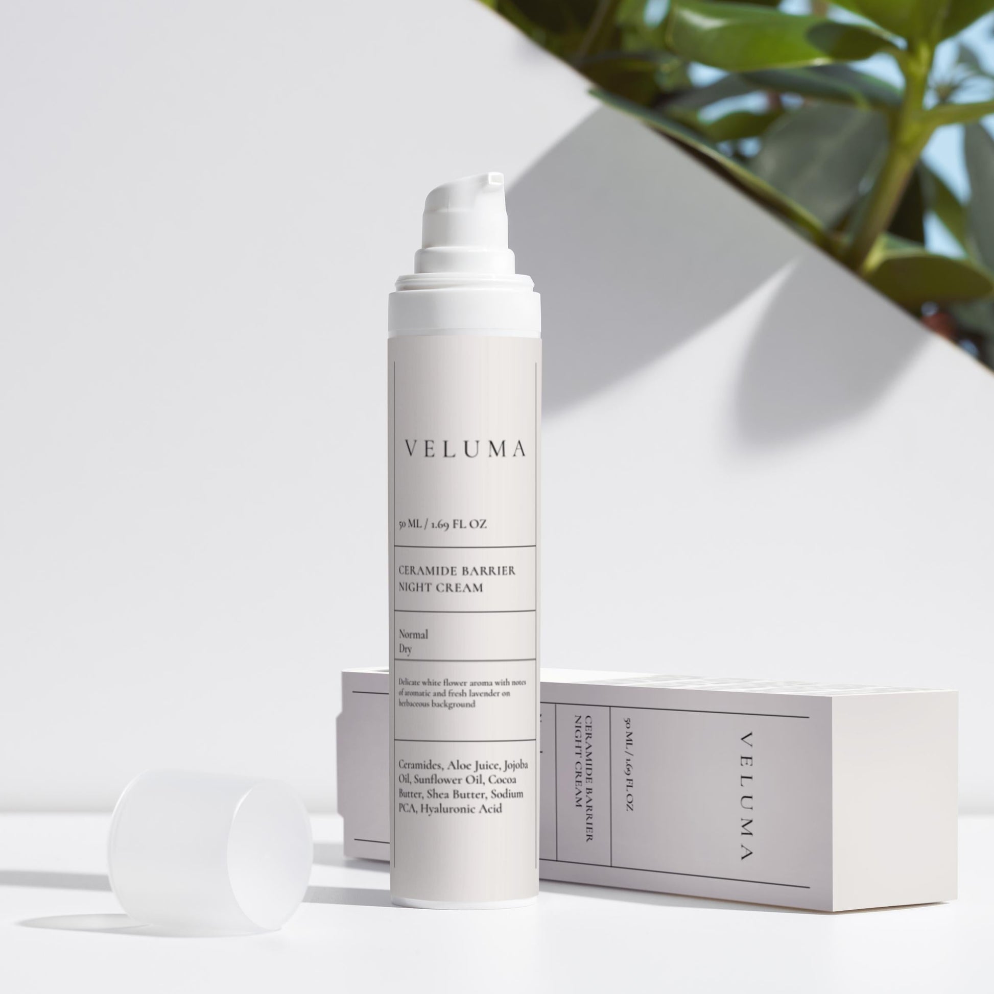 Veluma Skincare bottle with packaging on a white surface with greenery in the background